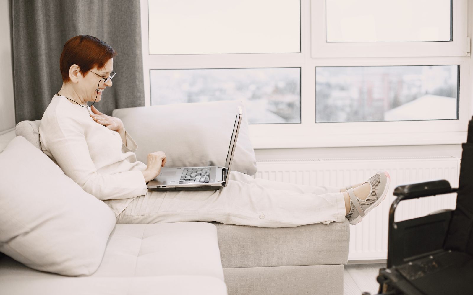 A woman smiling on a video call from her sofa